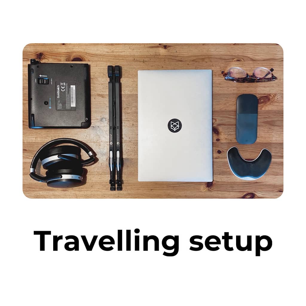 Image of my travelling setup, laptop, stand, mouse, keyboard, wrist support and headphones
