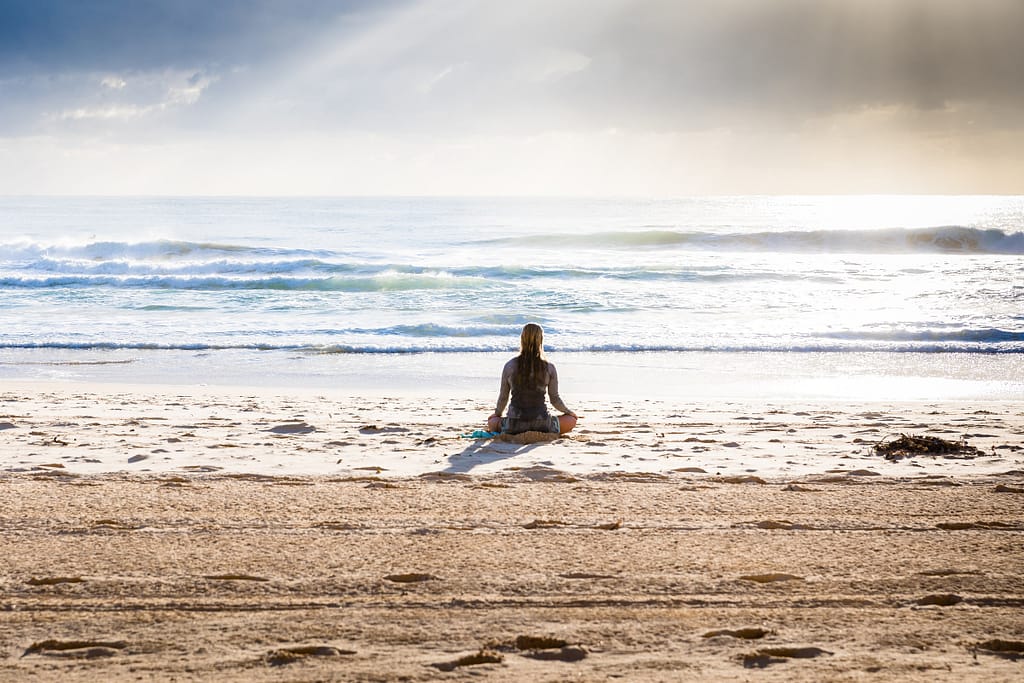 woman sat on the beach in meditation